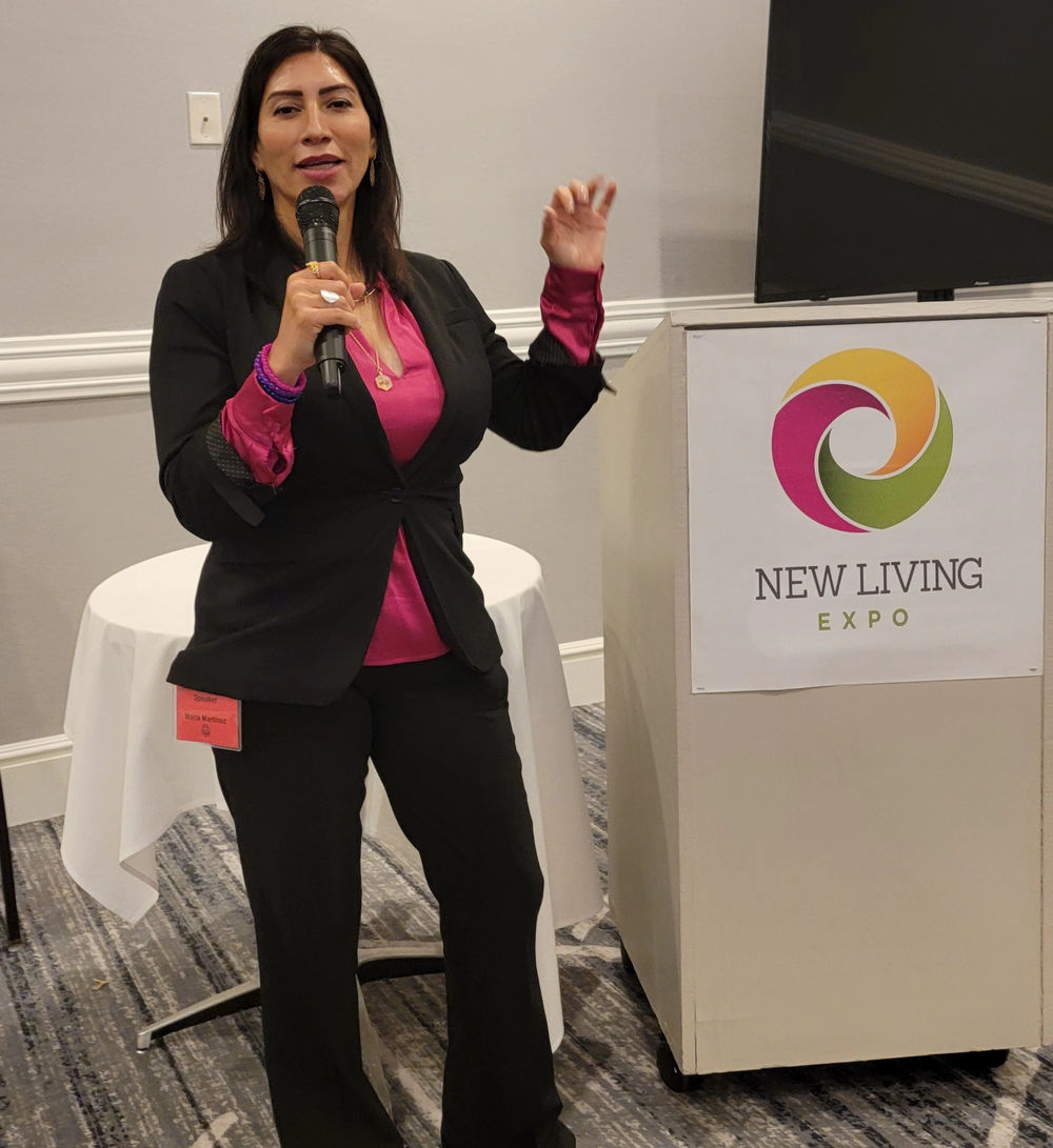 Maria Martinez speaking on stage at the New Living Expo