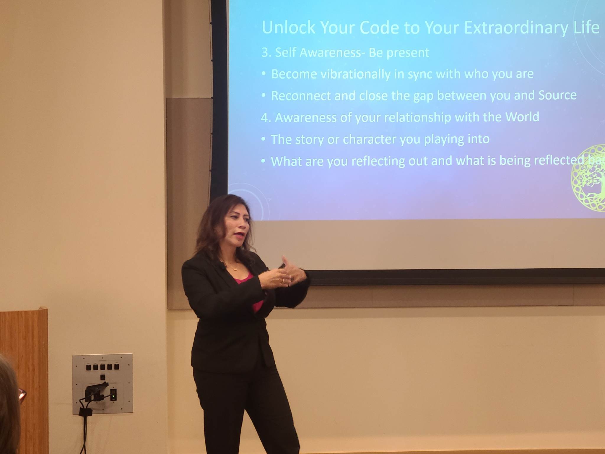 Maria Martinez presenting in a dark suit in front of a projection screen in a lecture room