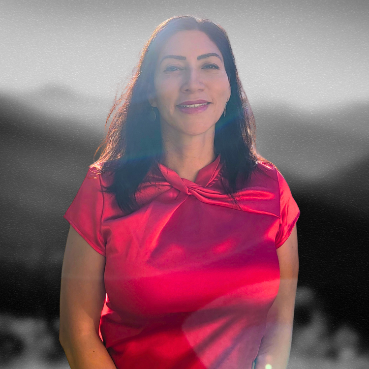 Maria Martinez in a red top, smiling, with a greyscale mountain landscape behind her